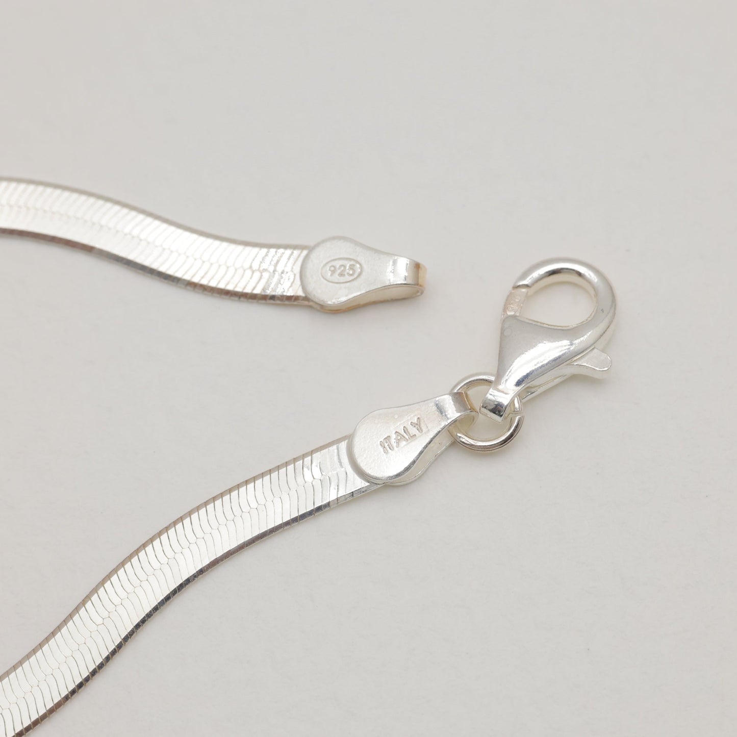 Silver necklace with clasp on a light gray background