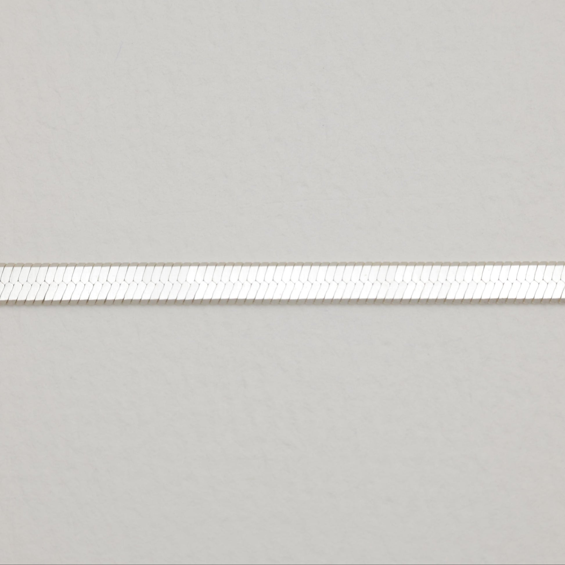 Close-up view of the silver herringbone chain pattern, showing its smooth, reflective surface.