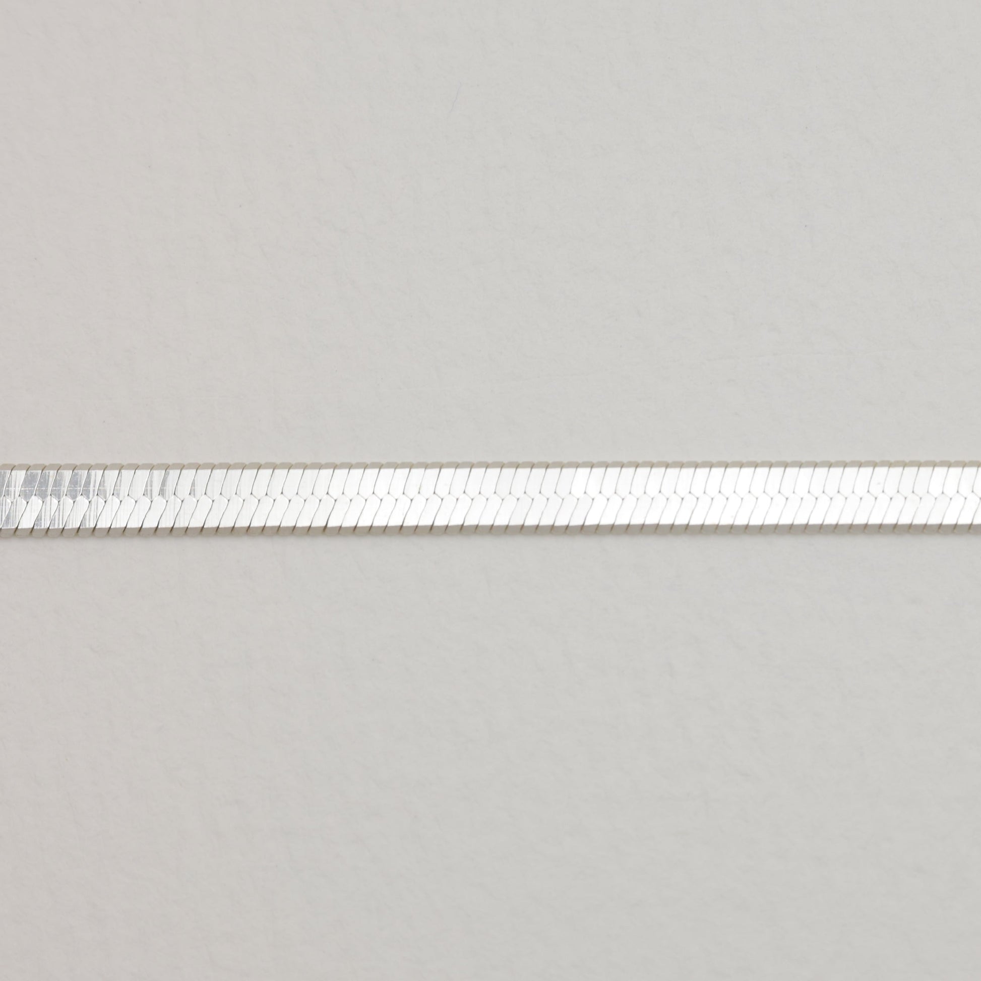 Zoomed view of the smooth, flat silver links in the herringbone chain design