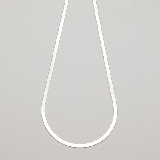 Full view of the Léa Herringbone Necklace laid flat in a teardrop shape against a neutral background.