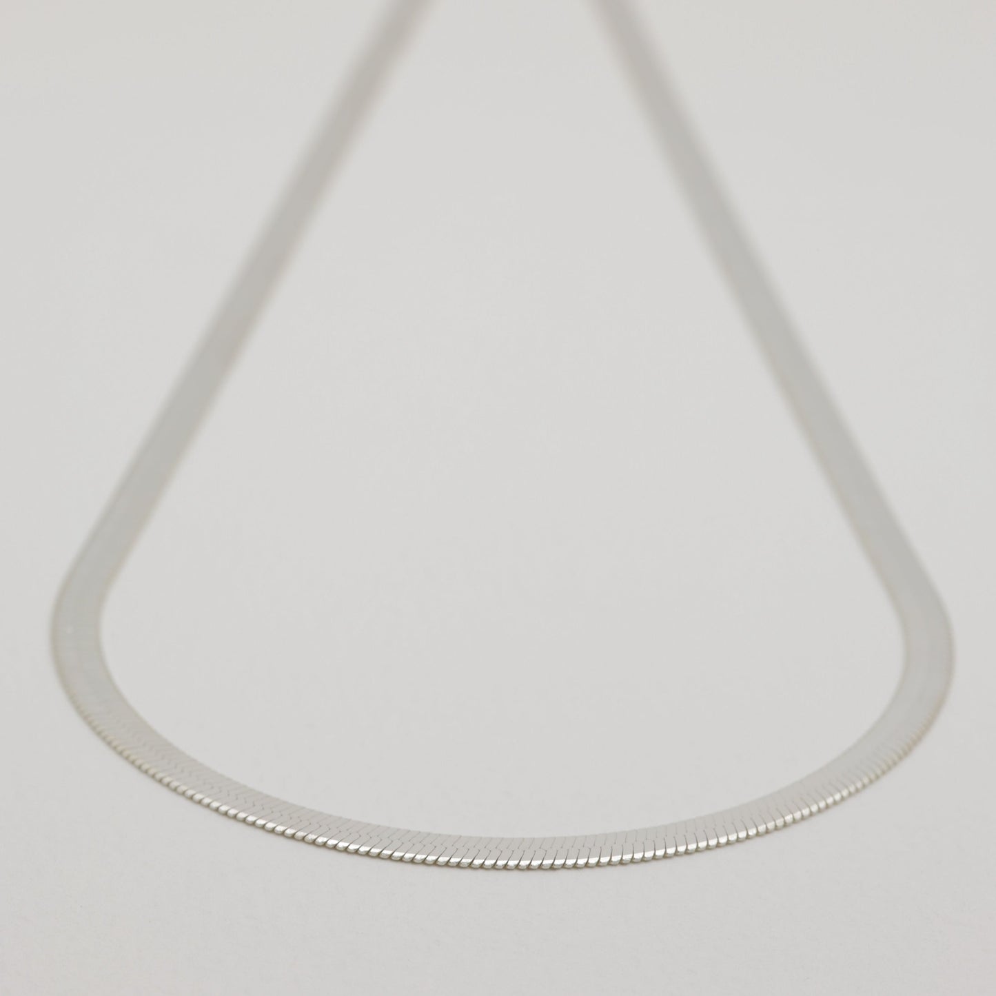 Minimal product shot of the full necklace, softly blurred at the clasp to highlight the chain’s shape.