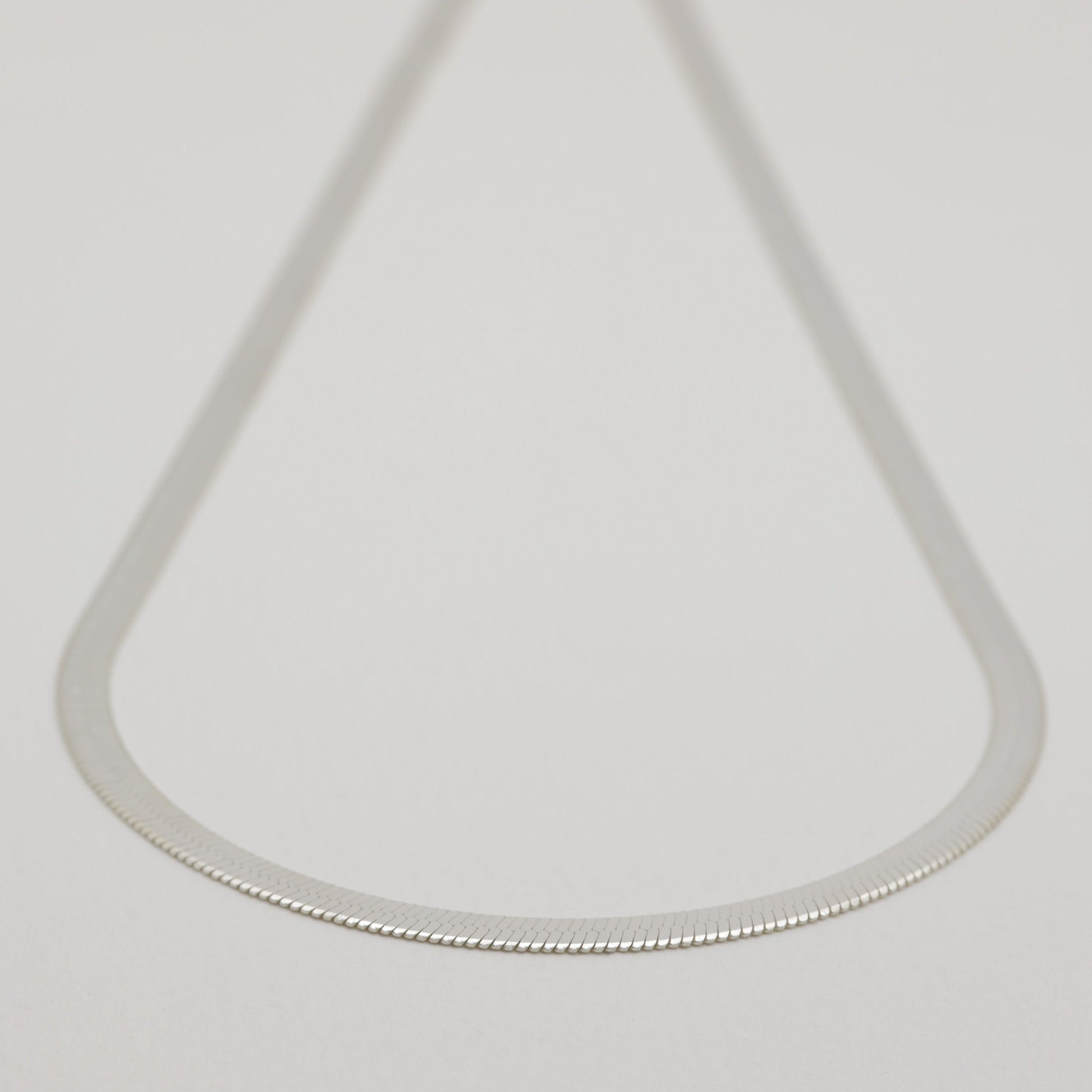 Minimal product shot of the full necklace, softly blurred at the clasp to highlight the chain’s shape.