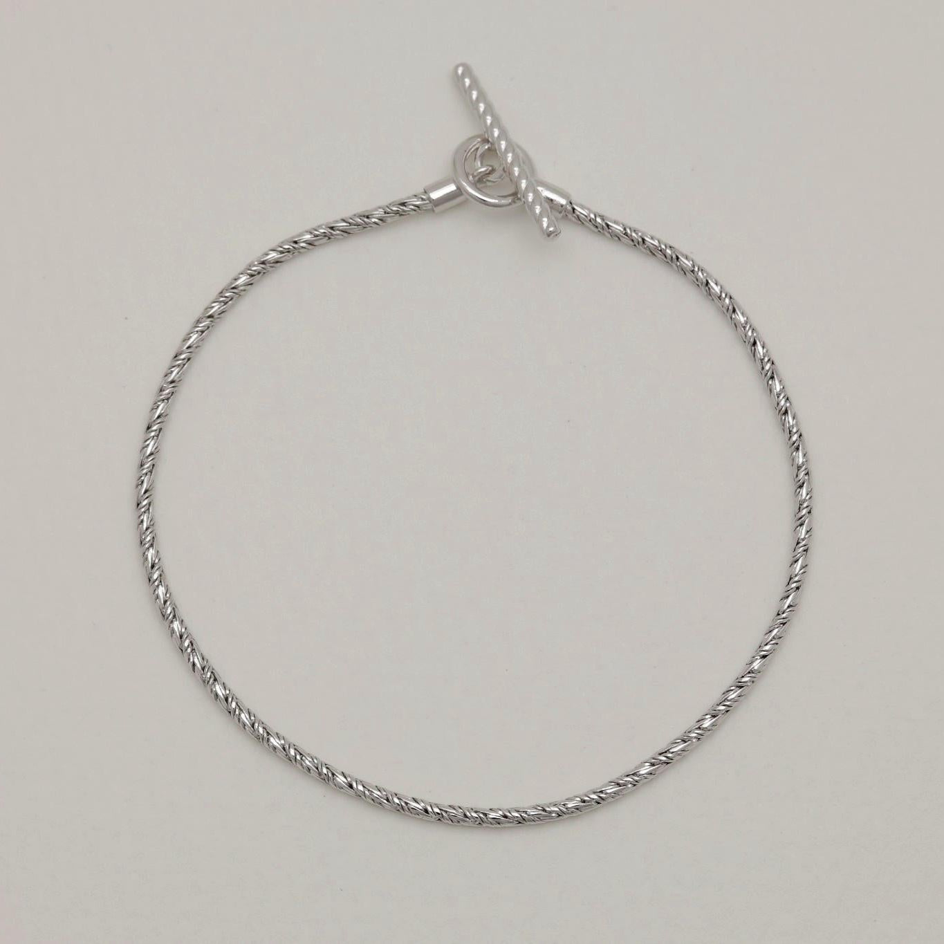 Flat-lay of the Érine Chain Bracelet showcasing its polished silver braid and classic shape.