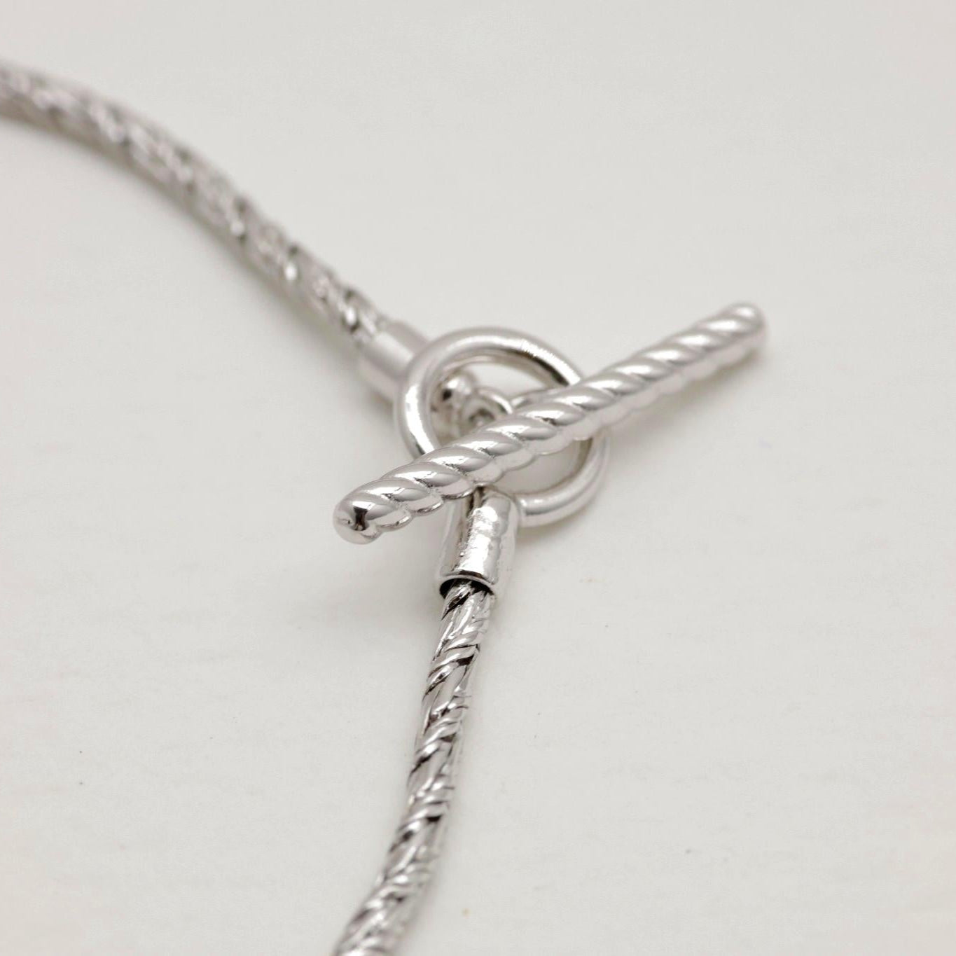 Close-up of the rope-detailed toggle clasp on the Érine Chain Bracelet in sterling silver.


