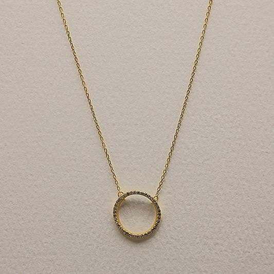 Close-up of gold vermeil necklace with open circle pendant set with cubic zirconia, shown on light background