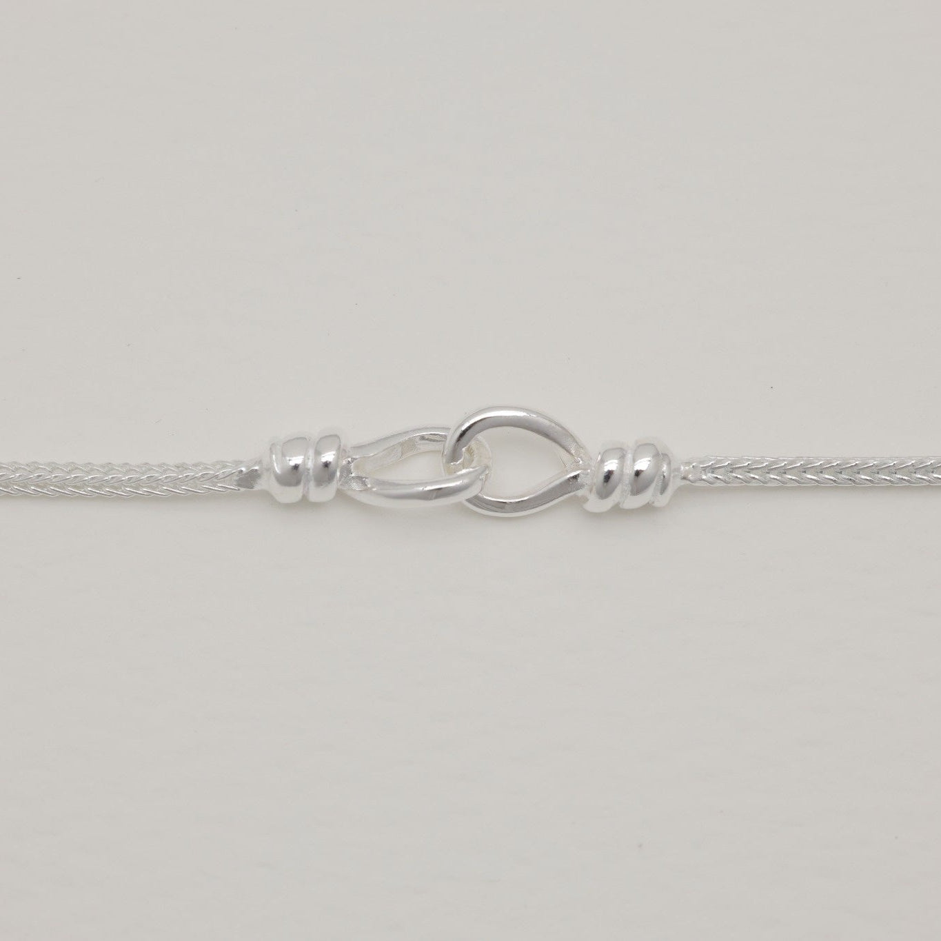 Sterling silver rope chain bracelet with clasp and adjustable links on light background.