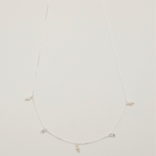 925 sterling silver necklace with cubic zirconia and natural pearl charms evenly spaced along a fine chain – MOA Jewelry flat lay