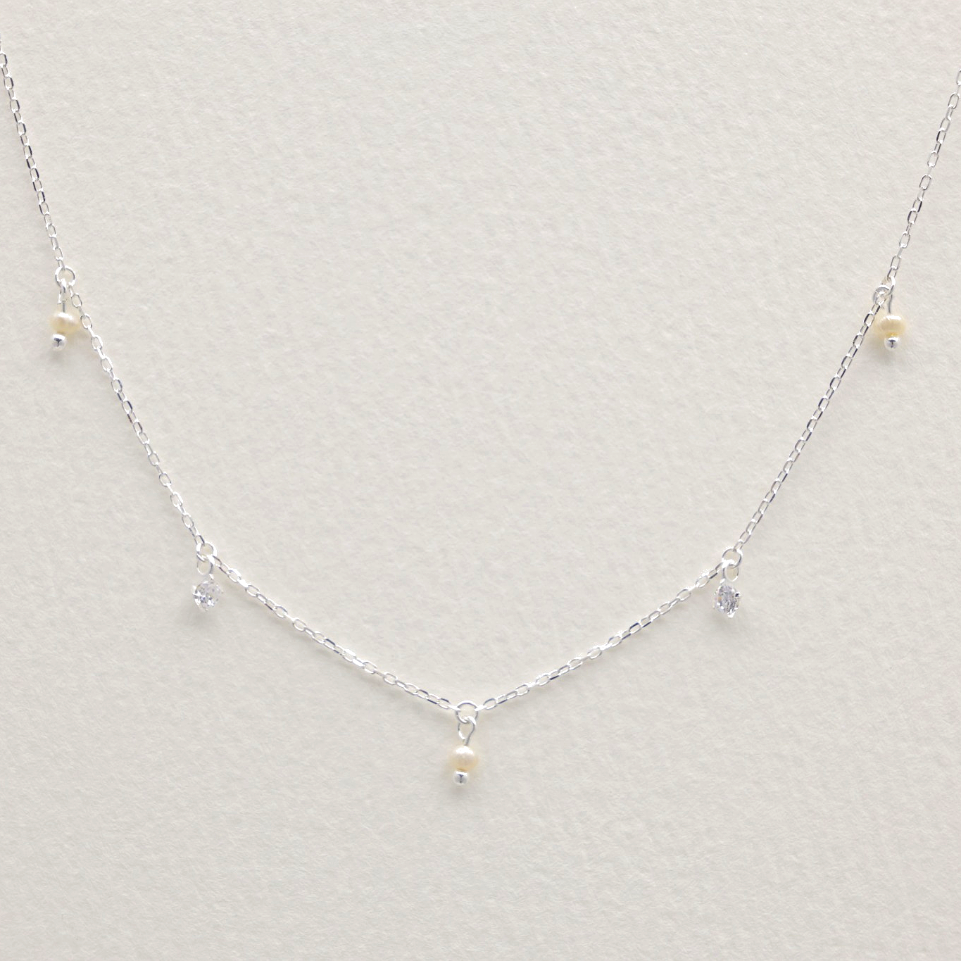 Close-up of Éliane Drop Necklace in sterling silver showing cubic zirconia and pearl details – modern delicate jewelry from MOA