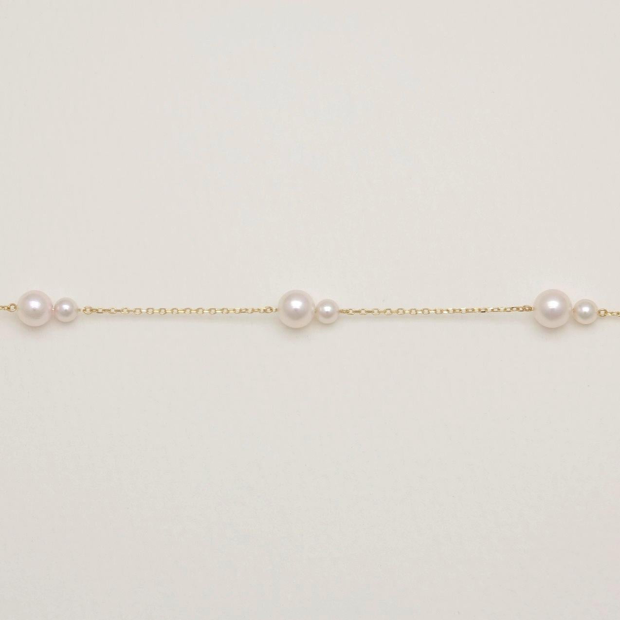 Gold chain with pearls on a light gray background