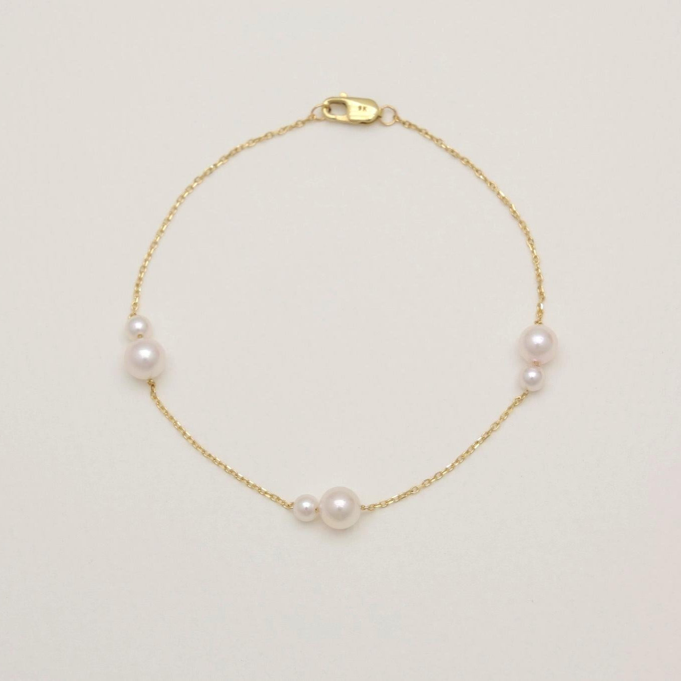Gold bracelet with pearls on a light beige background