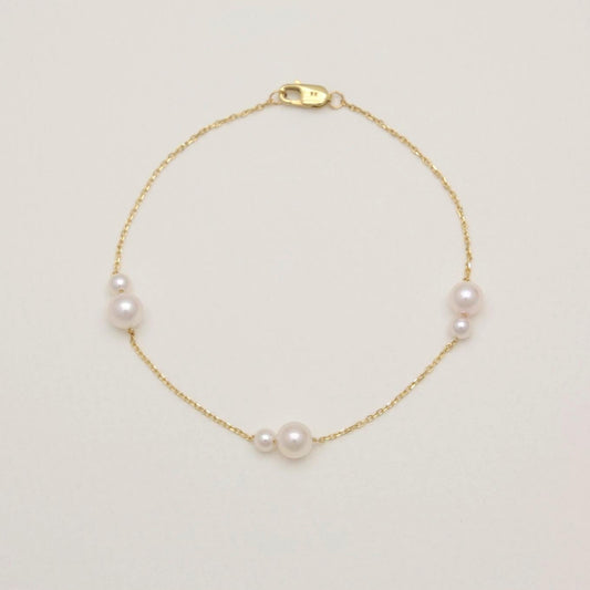 Gold bracelet with pearls on a light beige background