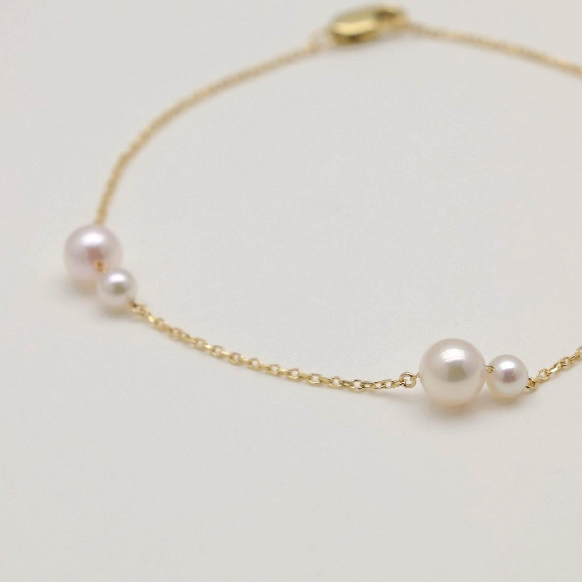 Gold bracelet with pearls on a light gray background