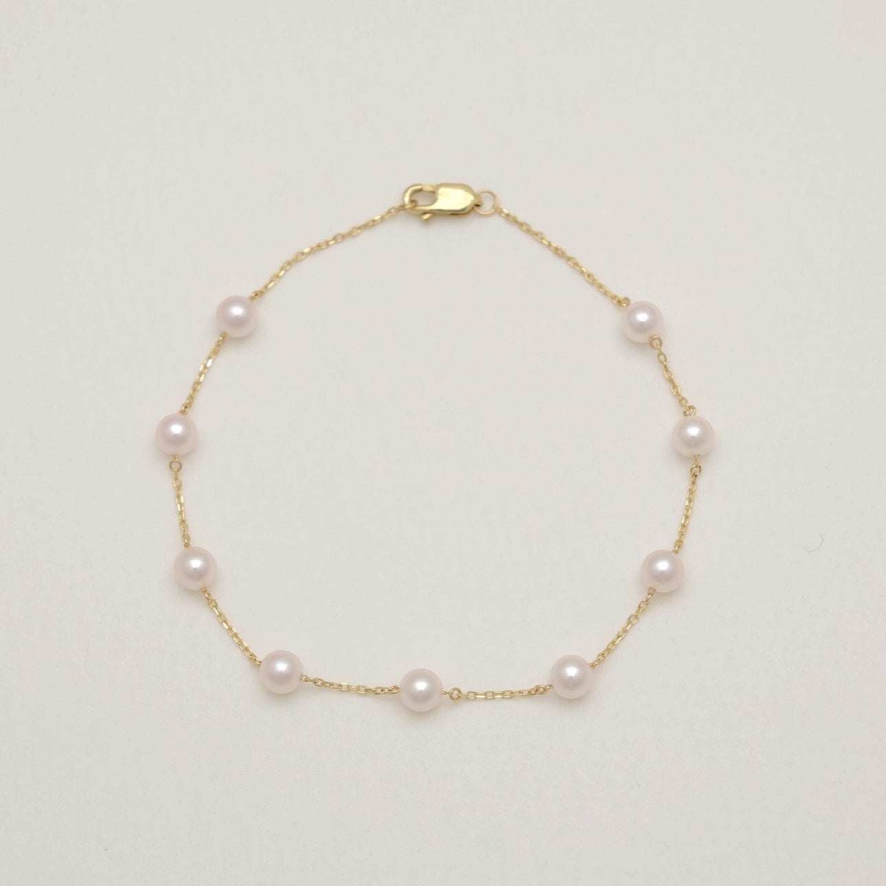 Gold bracelet with pearls on a light beige background
