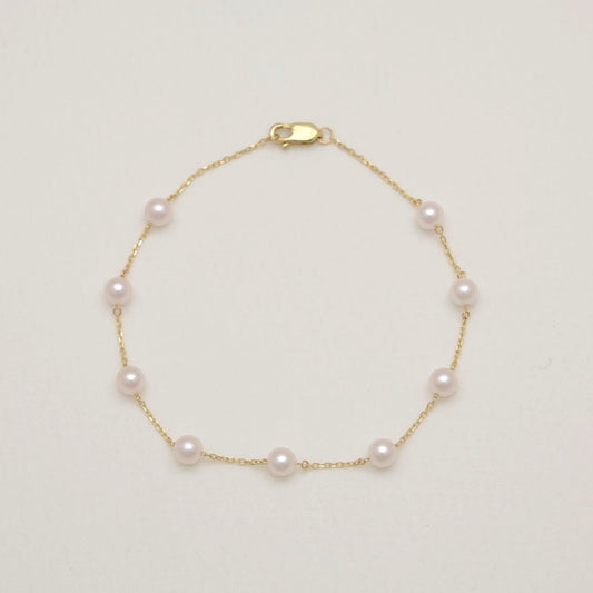 Gold bracelet with pearls on a light beige background