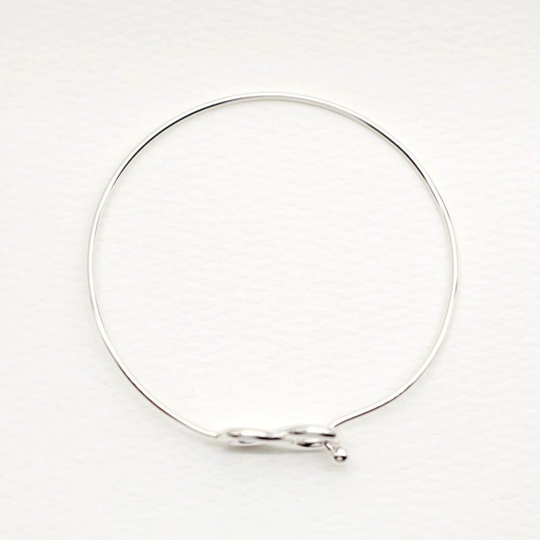 Infinity bangle bracelet in polished sterling silver on white background