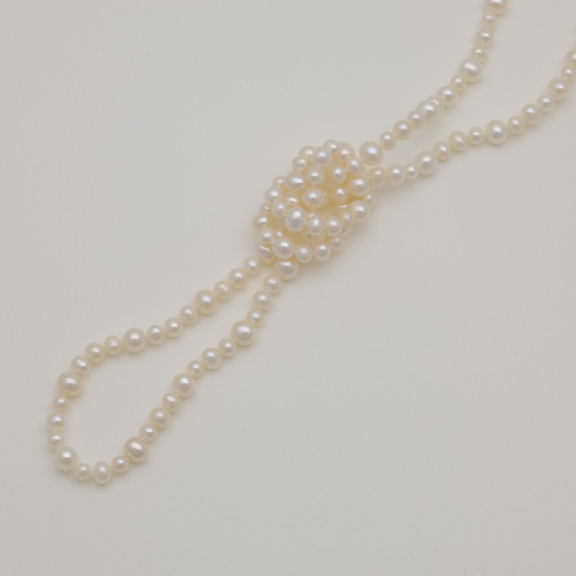 Freshwater pearl long necklace with natural luster, styled on cream background.