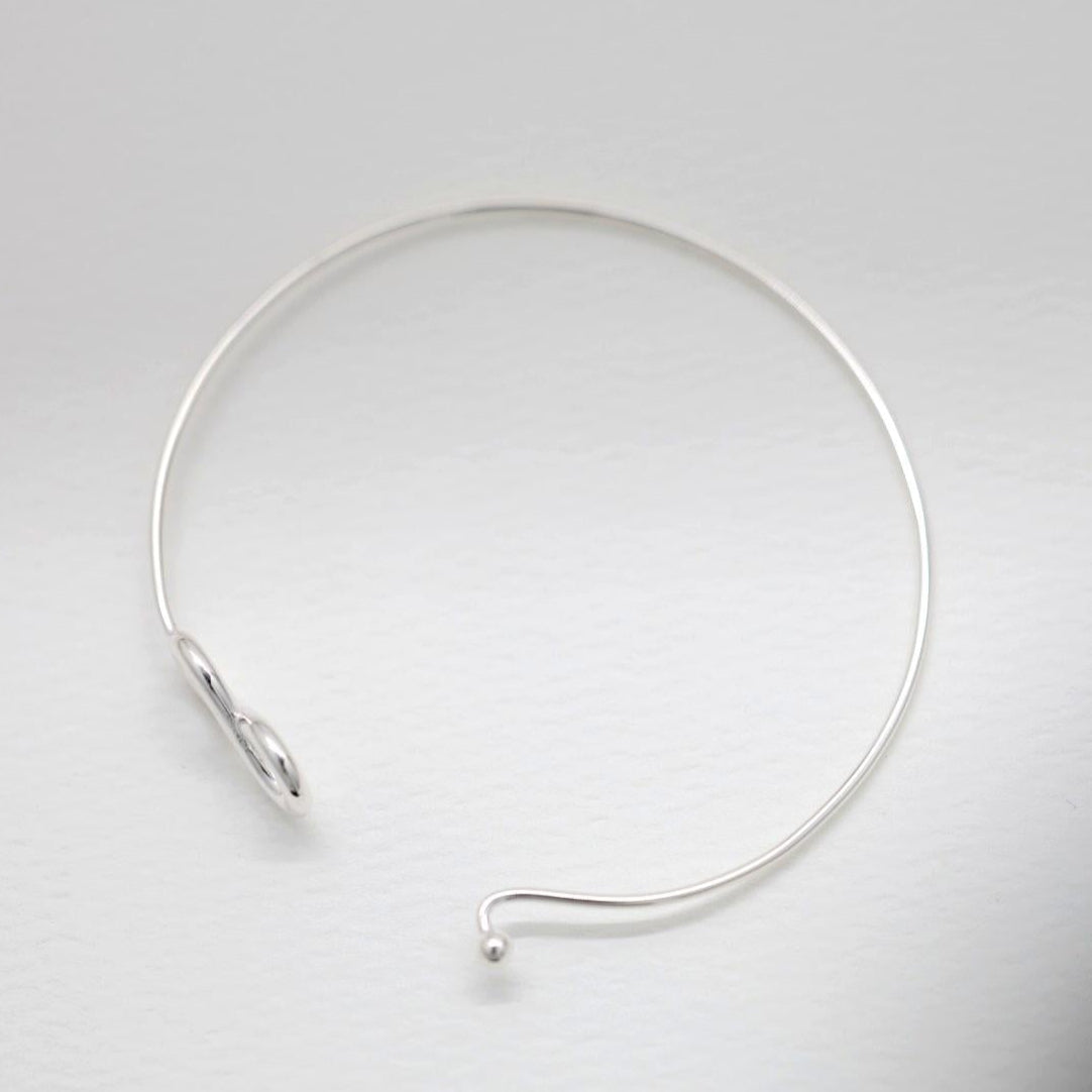 Infinity bangle bracelet in polished sterling silver on white background