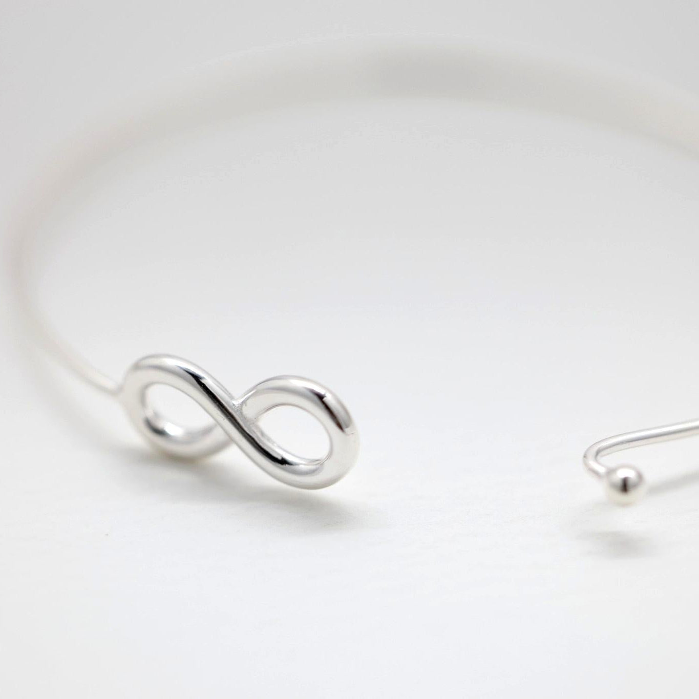 Infinity bangle bracelet in polished sterling silver on white background