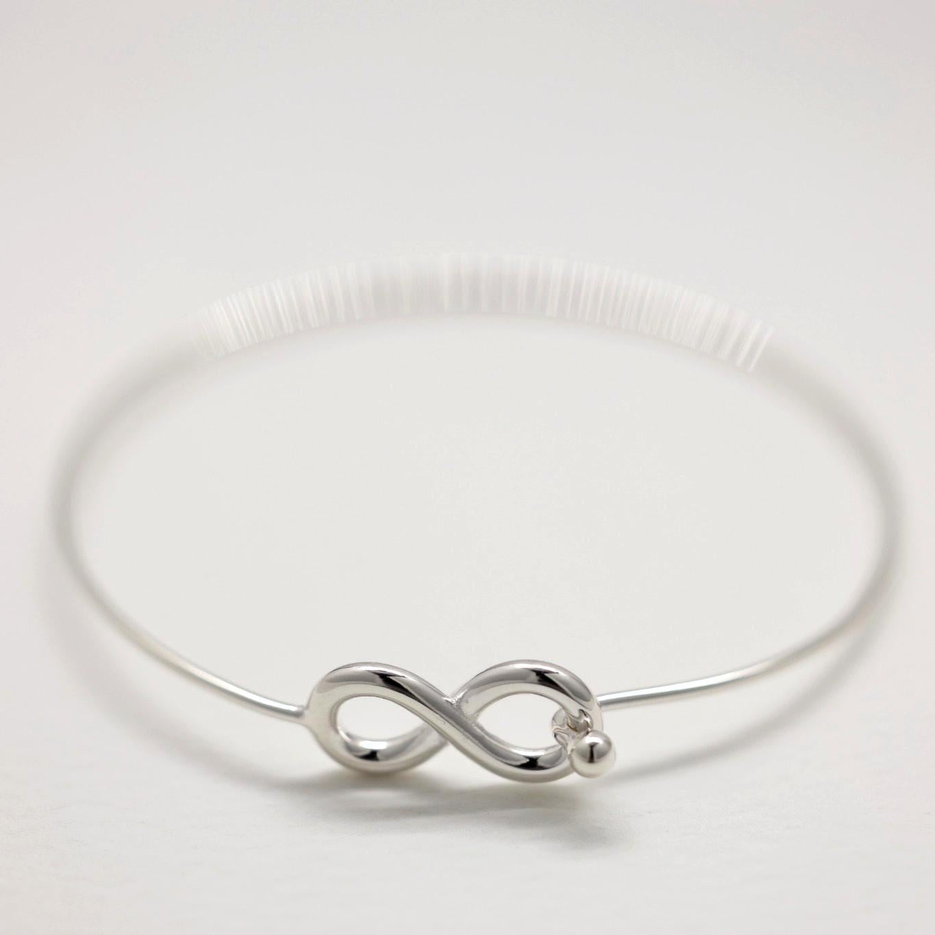 Infinity bangle bracelet in polished sterling silver on white background