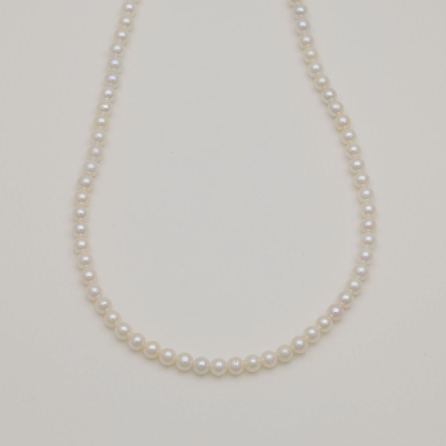 Freshwater pearl necklace with sterling silver clasp on cream background.