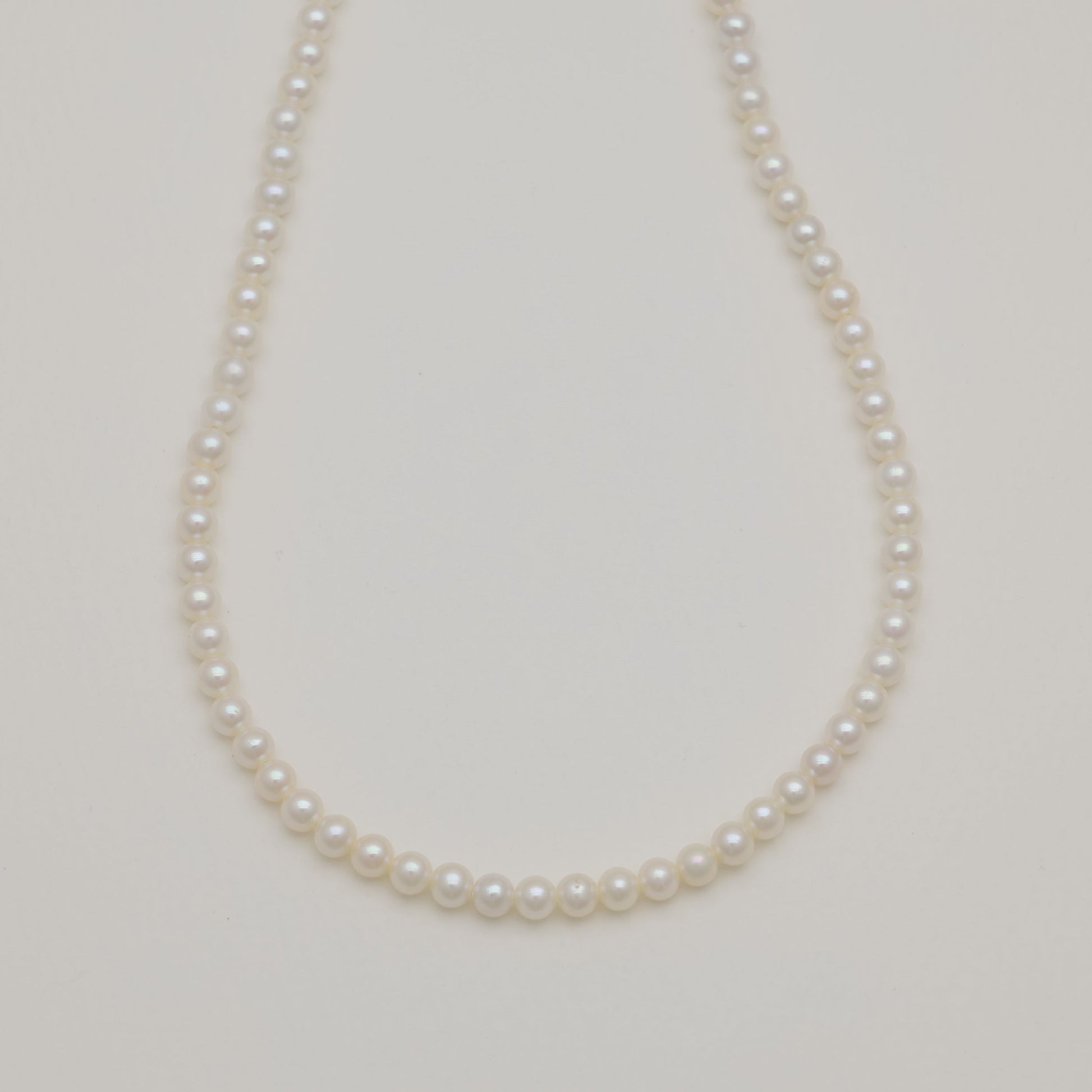 Freshwater pearl necklace with sterling silver clasp on cream background.