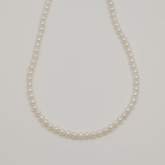 Freshwater pearl necklace with sterling silver clasp on cream background.