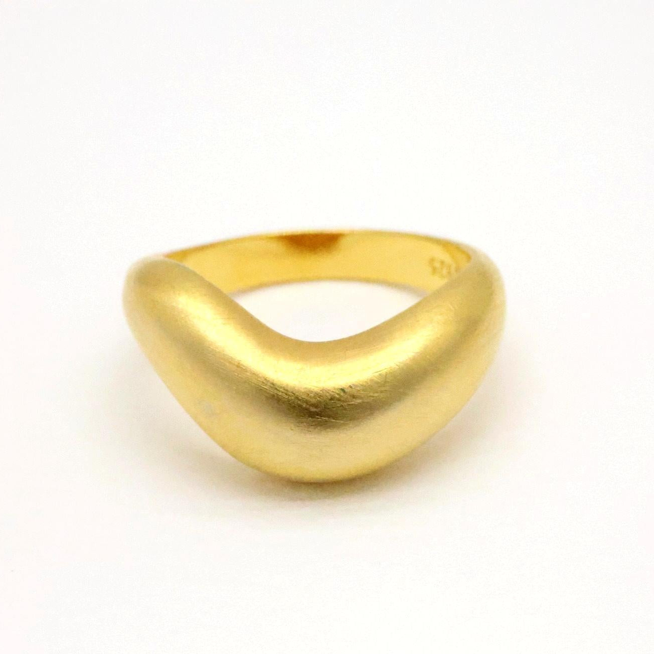 Matte gold vermeil sculptural ring with smooth organic curve, shown from a side angle on white background.