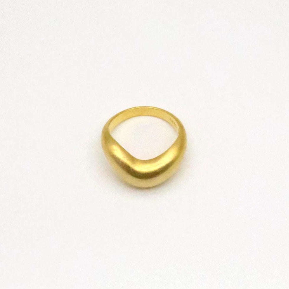 Matte gold vermeil sculptural ring with smooth organic curve, shown from a side angle on white background.