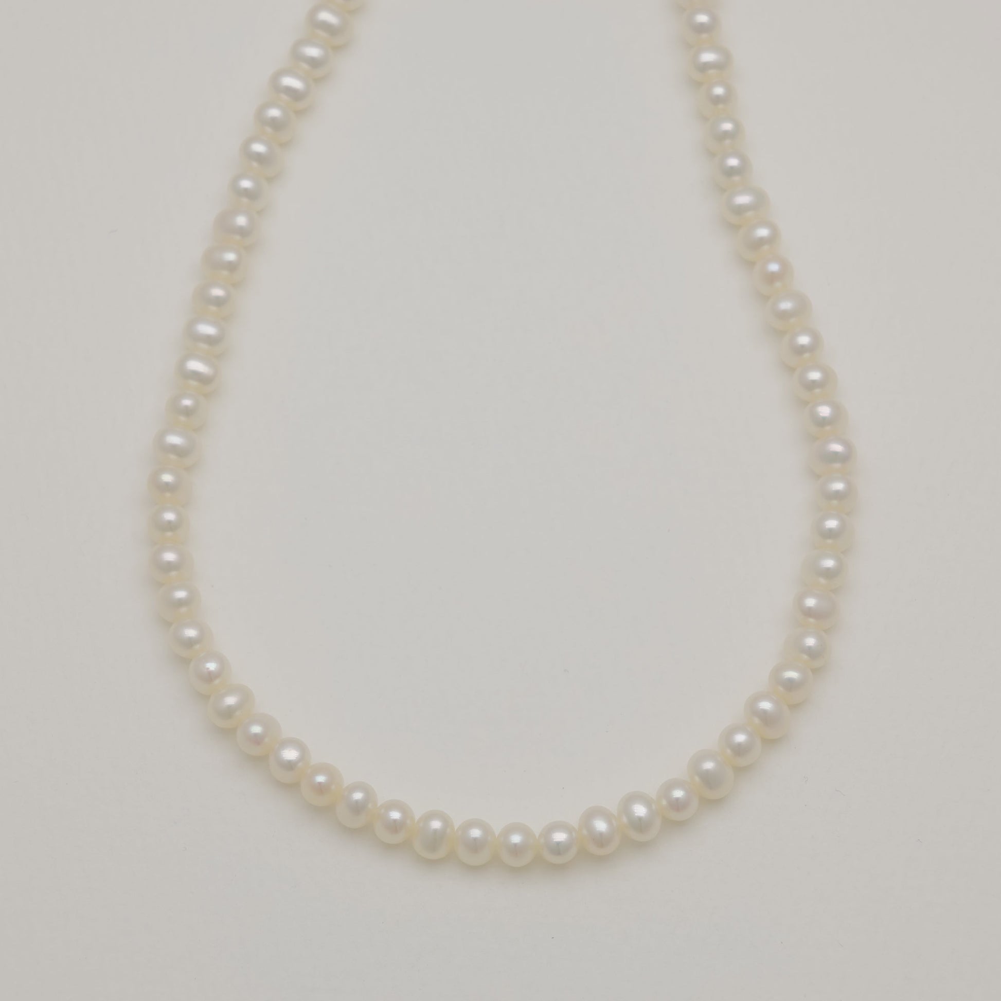 Pearl necklace on a light gray background