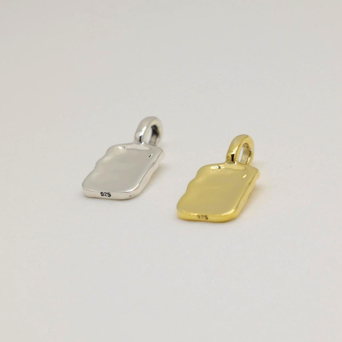 A softly contoured rectangular tag pendant in polished 925 sterling silver with rippled texture, styled on a white background.