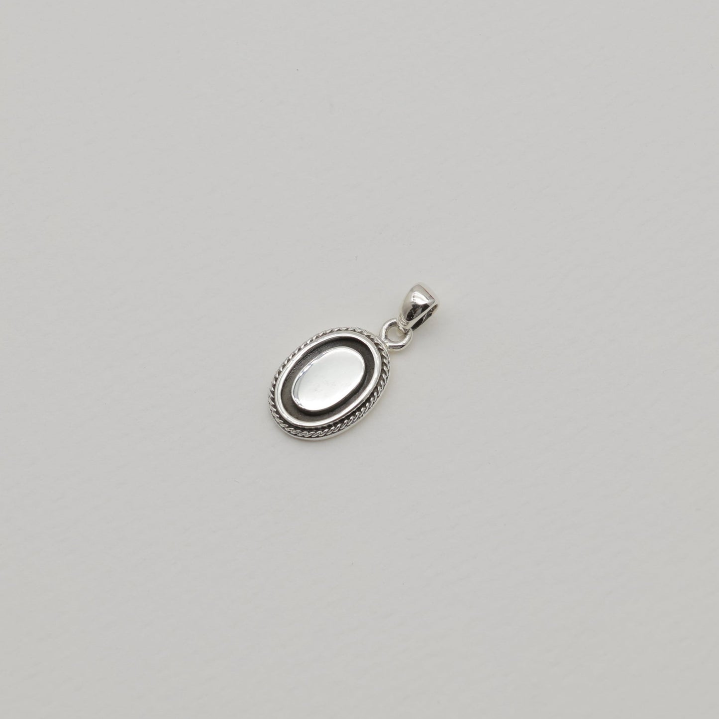 Sterling silver oval pendant with polished centre and oxidized rope edge, shown alone and styled with matching Séraphine ring.