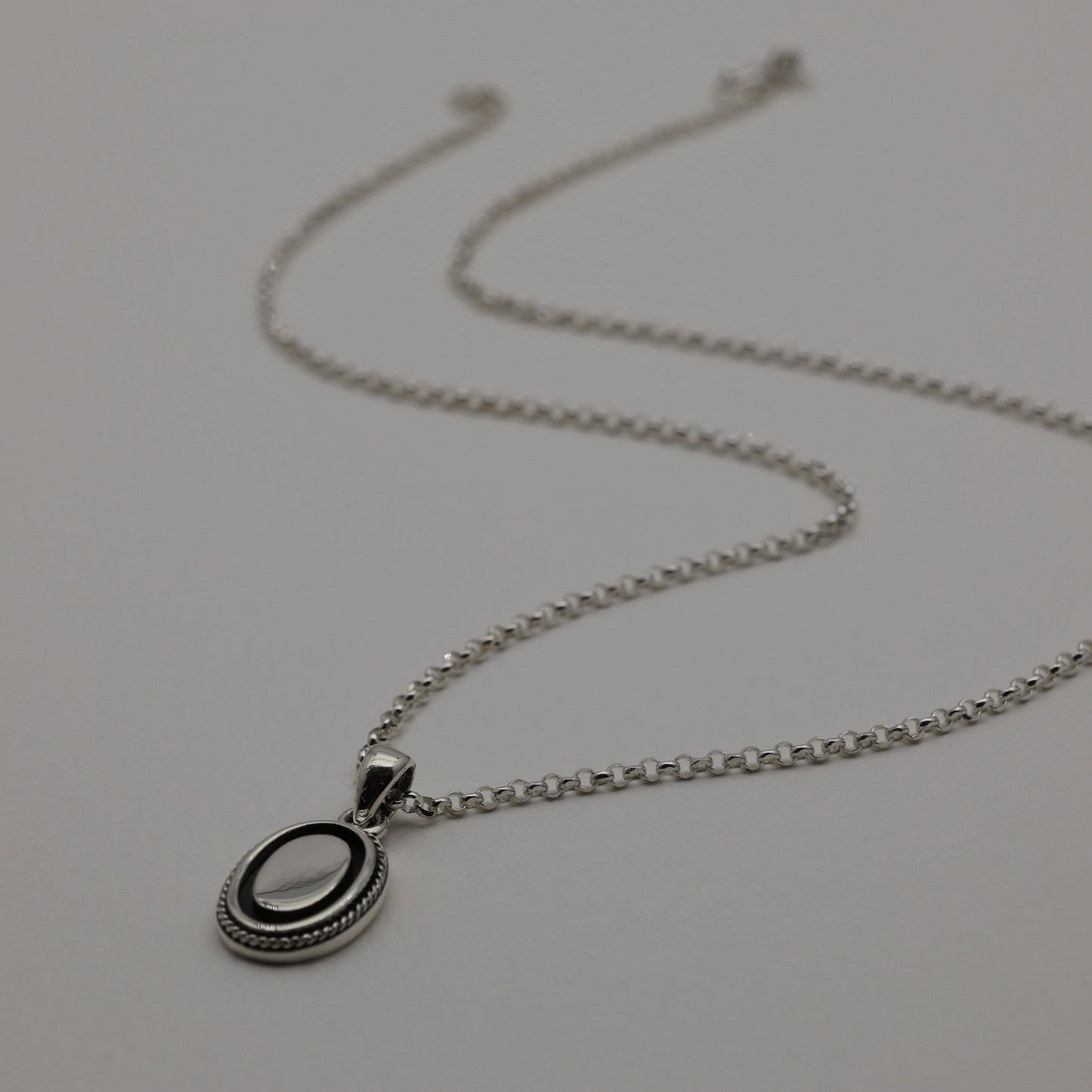 Sterling silver oval pendant with polished centre and oxidized rope edge, shown alone and styled with matching Séraphine ring.