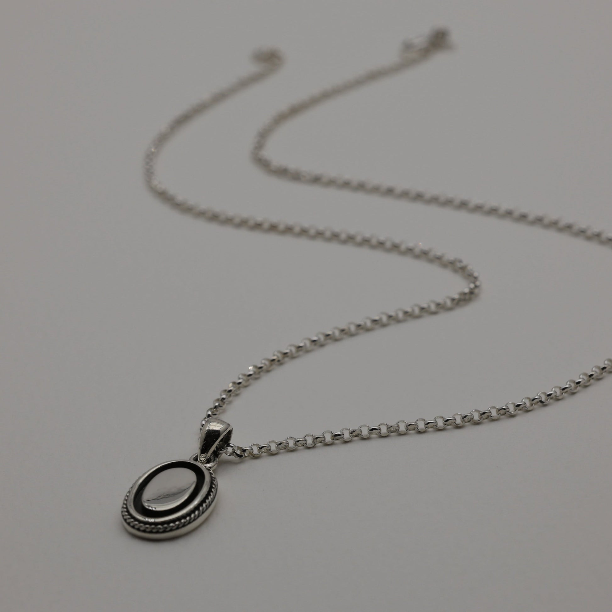 Sterling silver oval pendant with polished centre and oxidized rope edge, shown alone and styled with matching Séraphine ring.