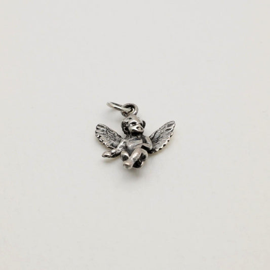 Sterling silver pendant in the shape of a seated cherub angel with wings, oxidized antique finish, photographed on a neutral background