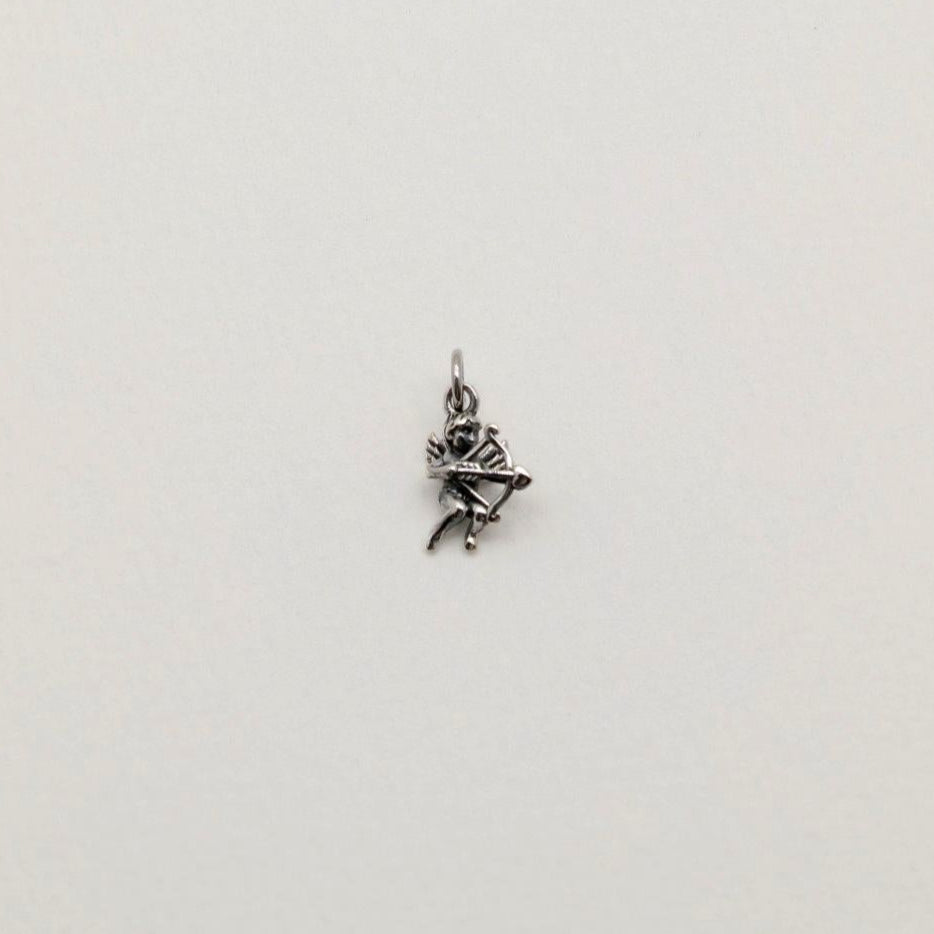 A sterling silver Cupid pendant charm featuring a bow and arrow, photographed on a soft white background.