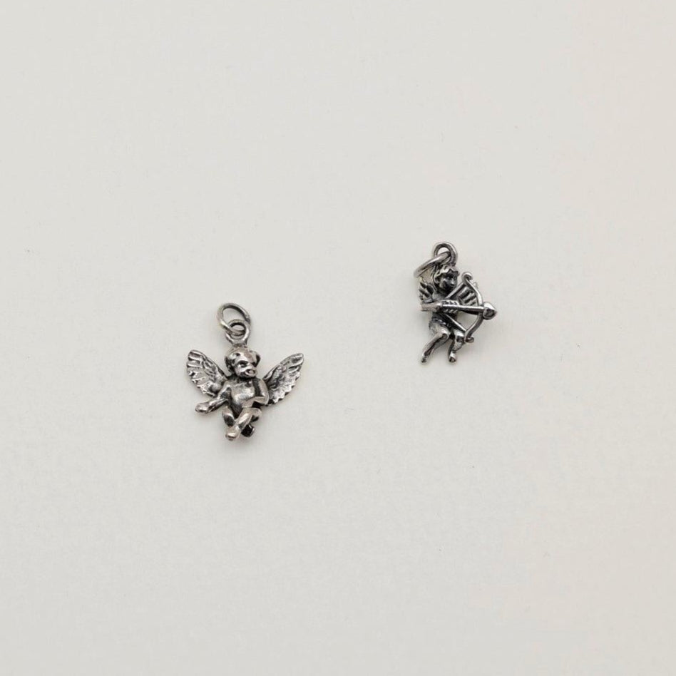 A sterling silver Cupid pendant charm featuring a bow and arrow, photographed on a soft white background.