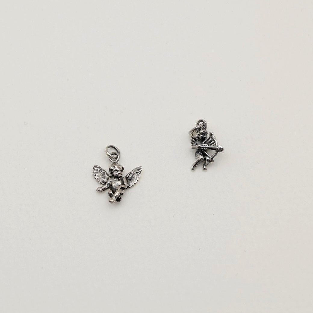Sterling silver pendant in the shape of a seated cherub angel with wings, oxidized antique finish, photographed on a neutral background