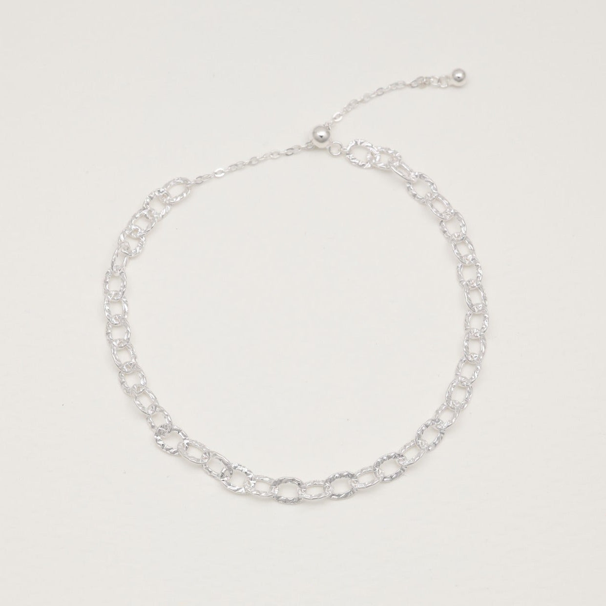 Sterling silver loop bracelet with hammered links on white background"