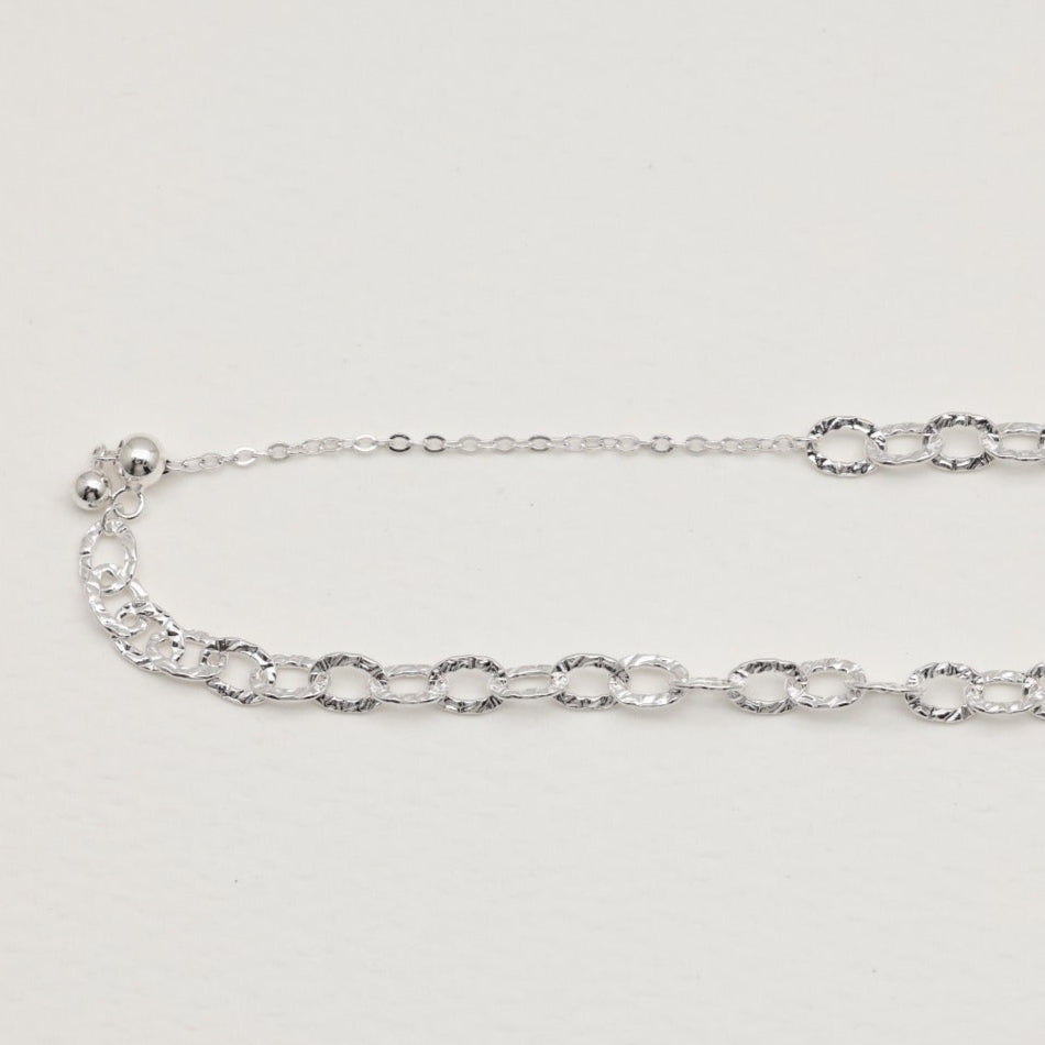 Sterling silver loop bracelet with hammered links on white background"