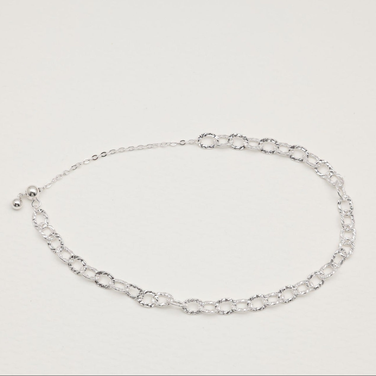 Sterling silver loop bracelet with hammered links on white background"