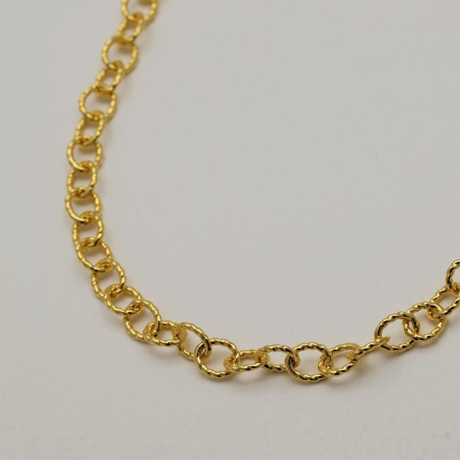 Gold chain necklace on a light gray background