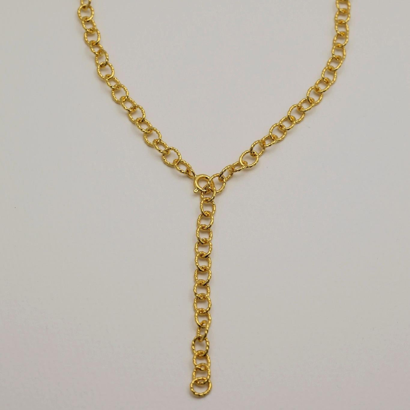 Gold chain necklace on a light gray background