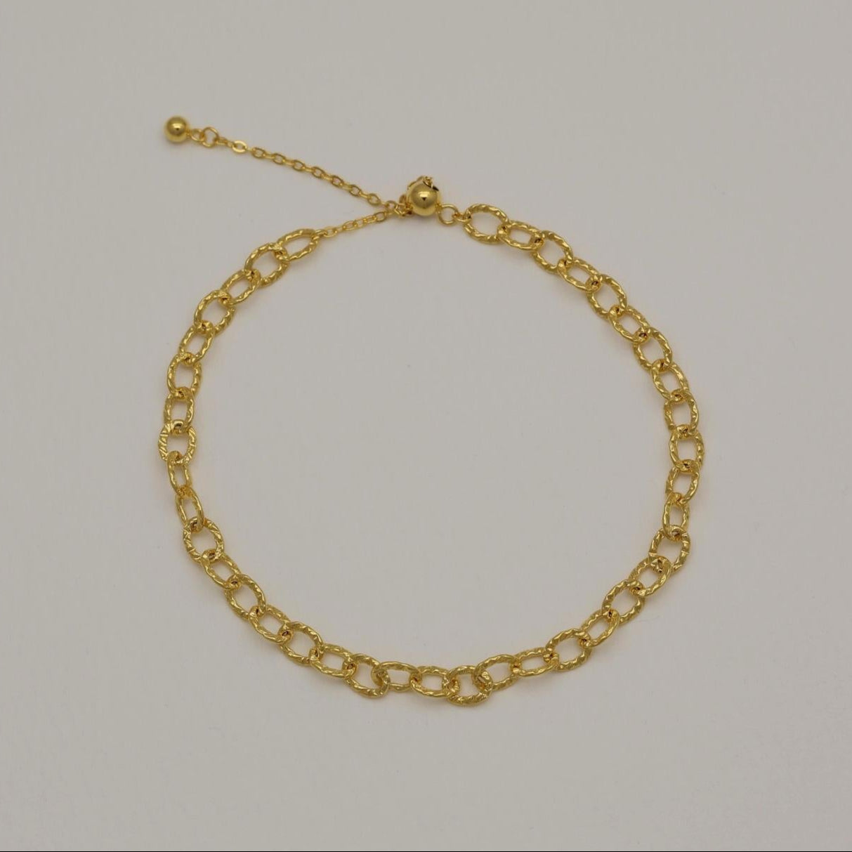 Gold vermeil bracelet featuring twisted loop chain links with polished finish, shown on neutral background.