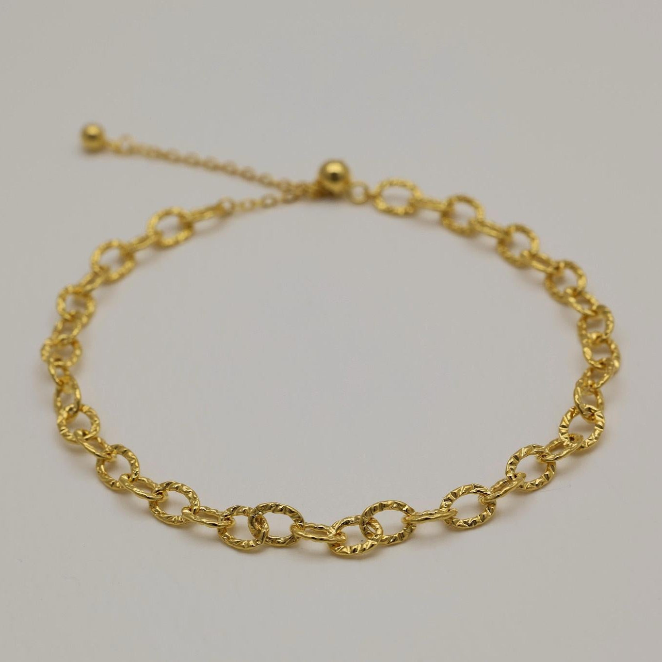 Gold vermeil bracelet featuring twisted loop chain links with polished finish, shown on neutral background.