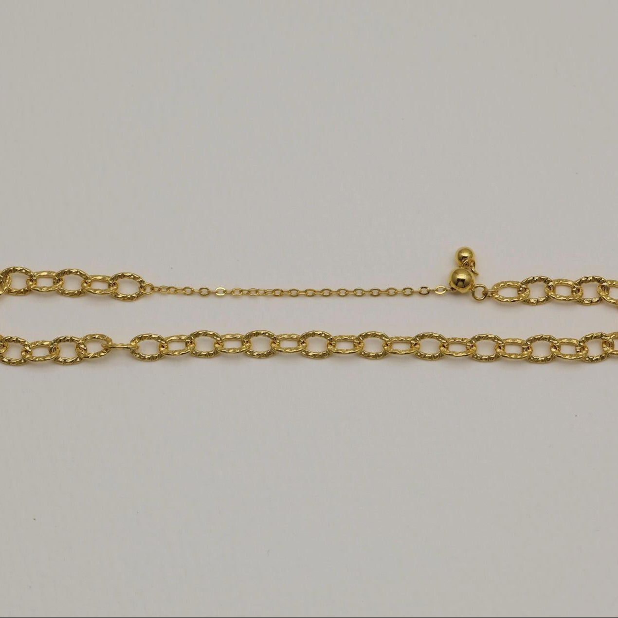 Gold vermeil bracelet featuring twisted loop chain links with polished finish, shown on neutral background.
