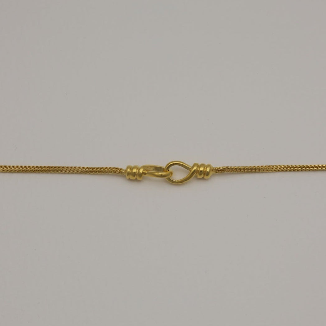 Gold vermeil bracelet with braided chain and loop detail, laid flat and in a circular shape.