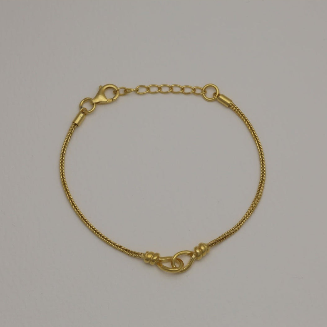 Gold vermeil bracelet with braided chain and loop detail, laid flat and in a circular shape.