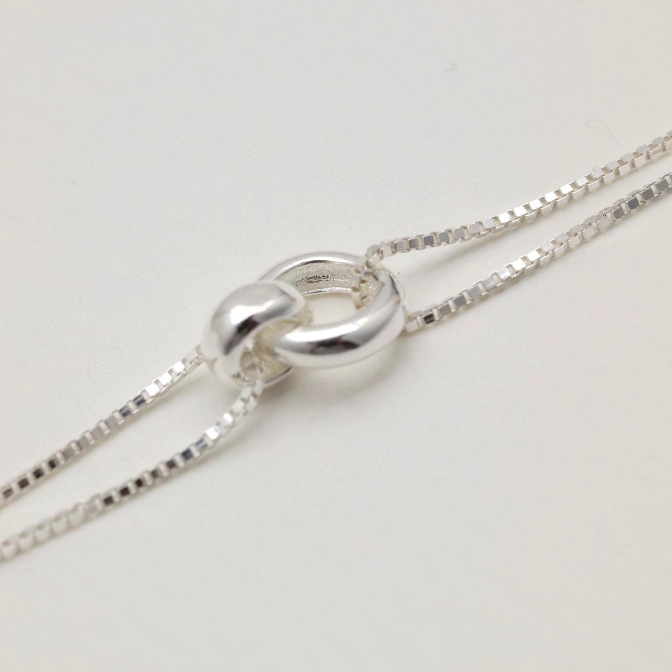 Silver necklace with a unique clasp on a light gray background