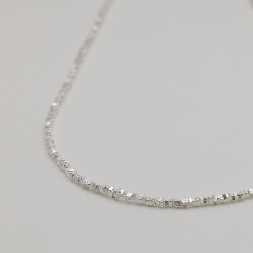 Close-up of the Victoire Textured Chain Necklace in sterling silver on a neutral background