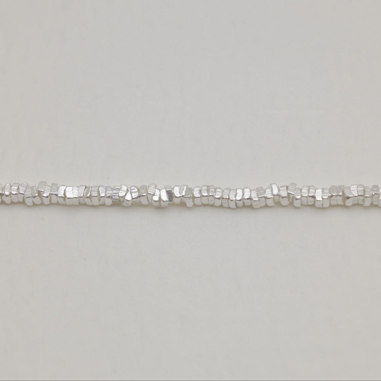 Macro detail of the faceted square links showing the chain’s textured polish